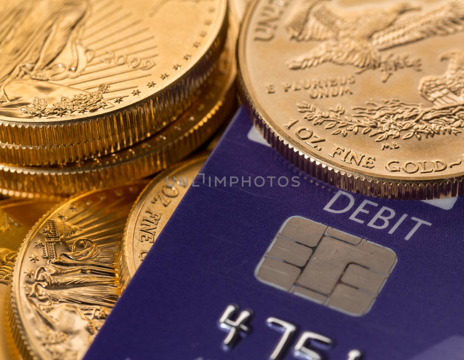 Solid gold coins contrasted with debit word on plastic credit card suggesting debt problems
