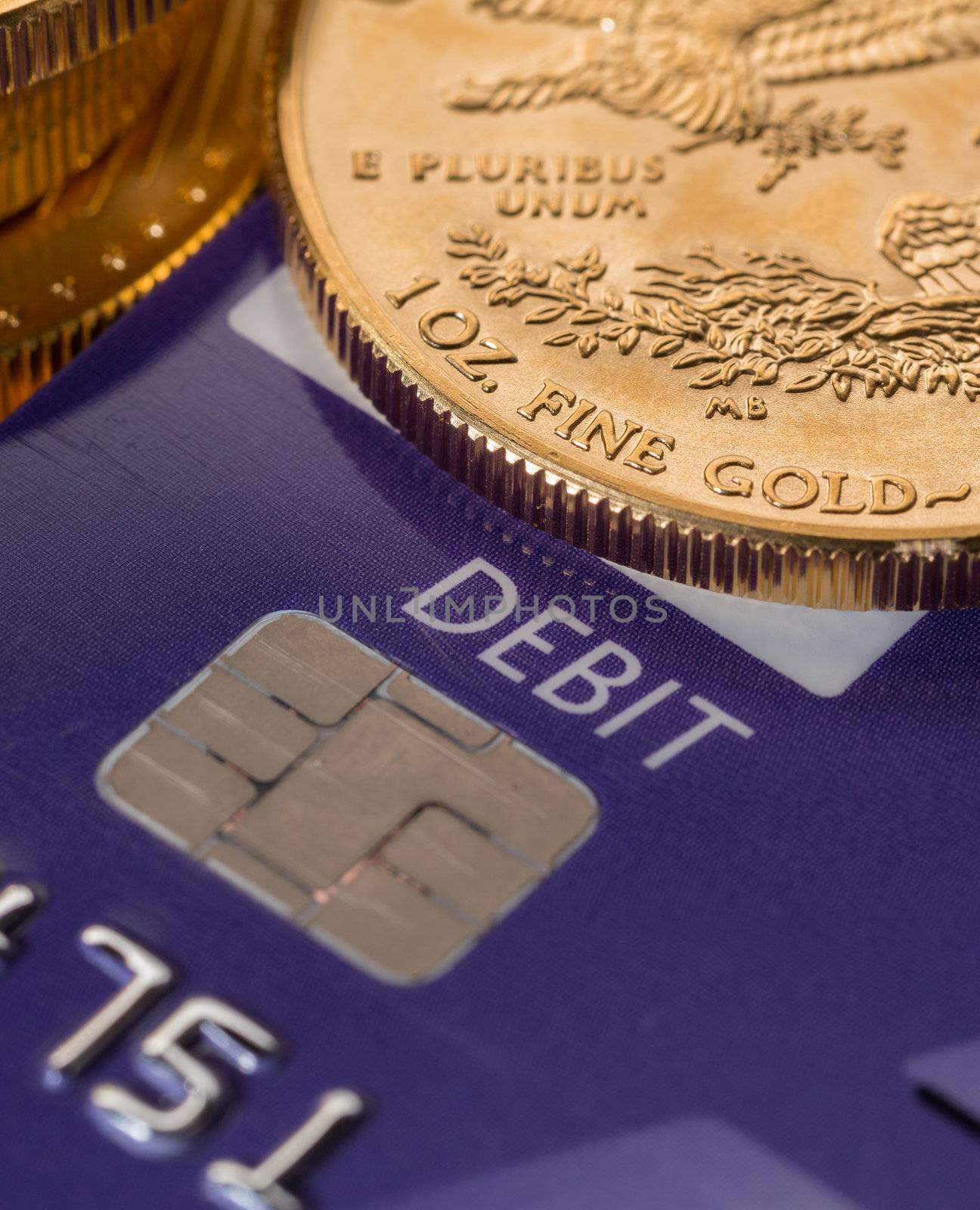 Solid gold coins contrasted with debit word on plastic credit card suggesting debt problems