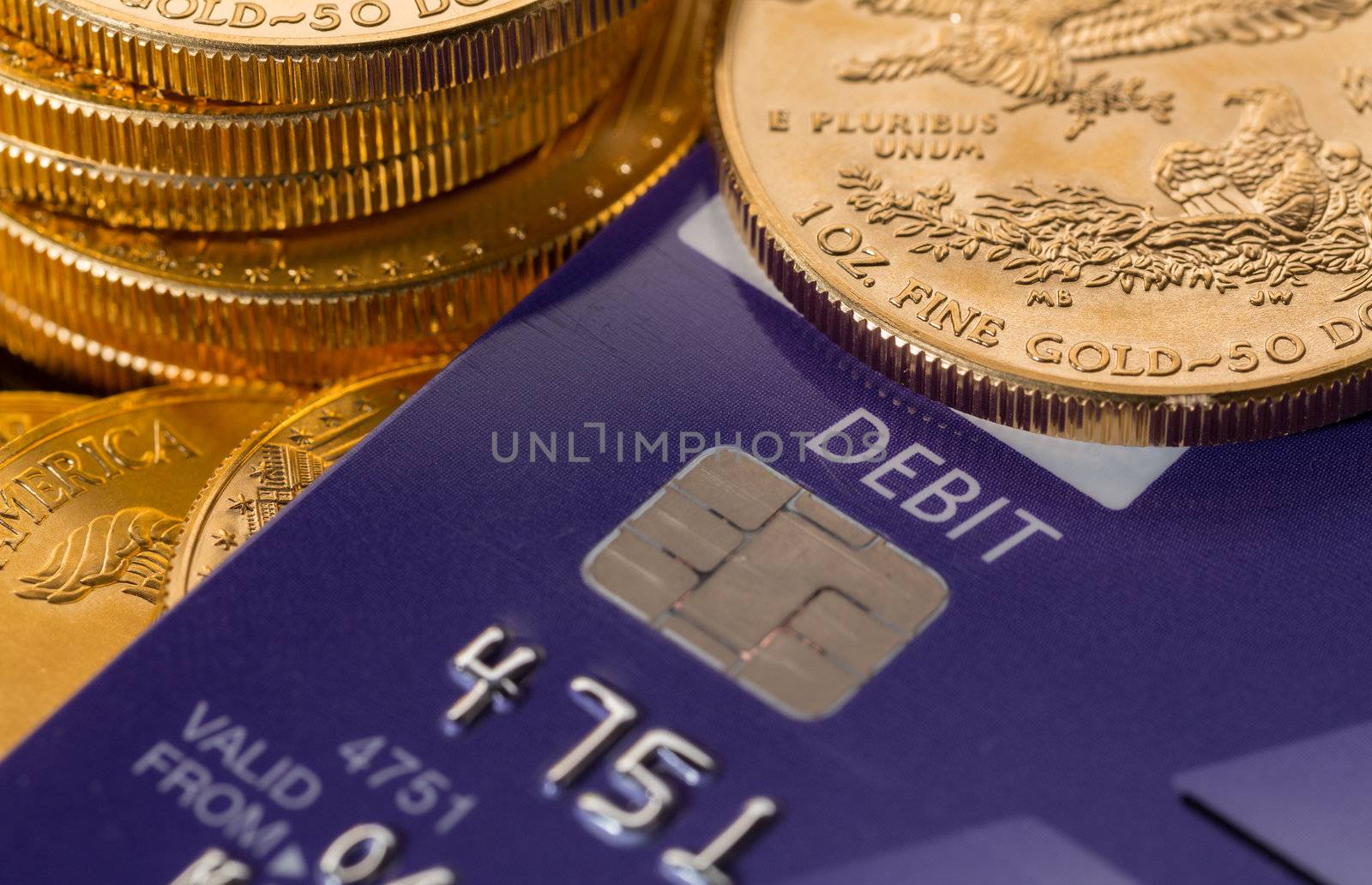Solid gold coins contrasted with debit word on plastic credit card suggesting debt problems