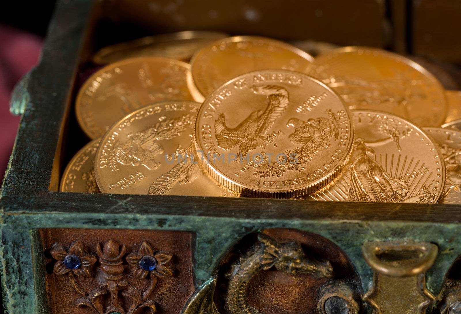 Stacks of gold eagle one troy ounce golden coins from US Treasury mint in old carved pirate treasure chest