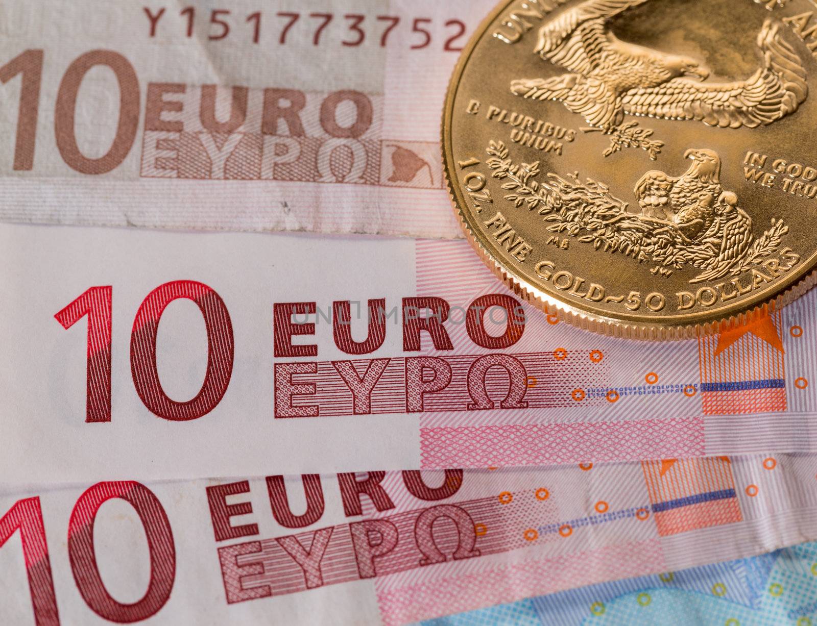 Solid gold coins contrasted with numbers on euro note suggesting debt problems