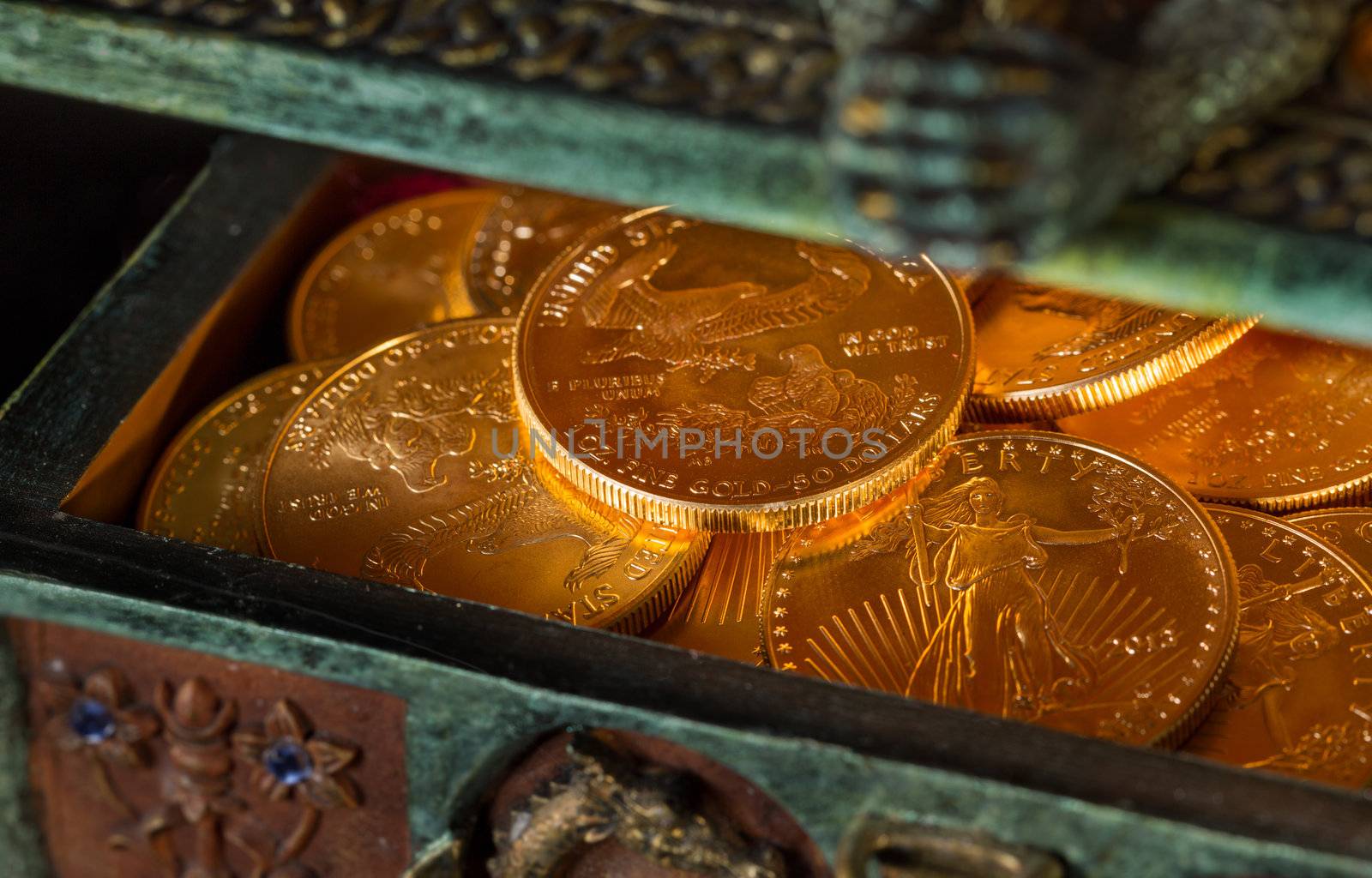 Stacks of gold eagle one troy ounce golden coins from US Treasury mint in old carved pirate treasure chest
