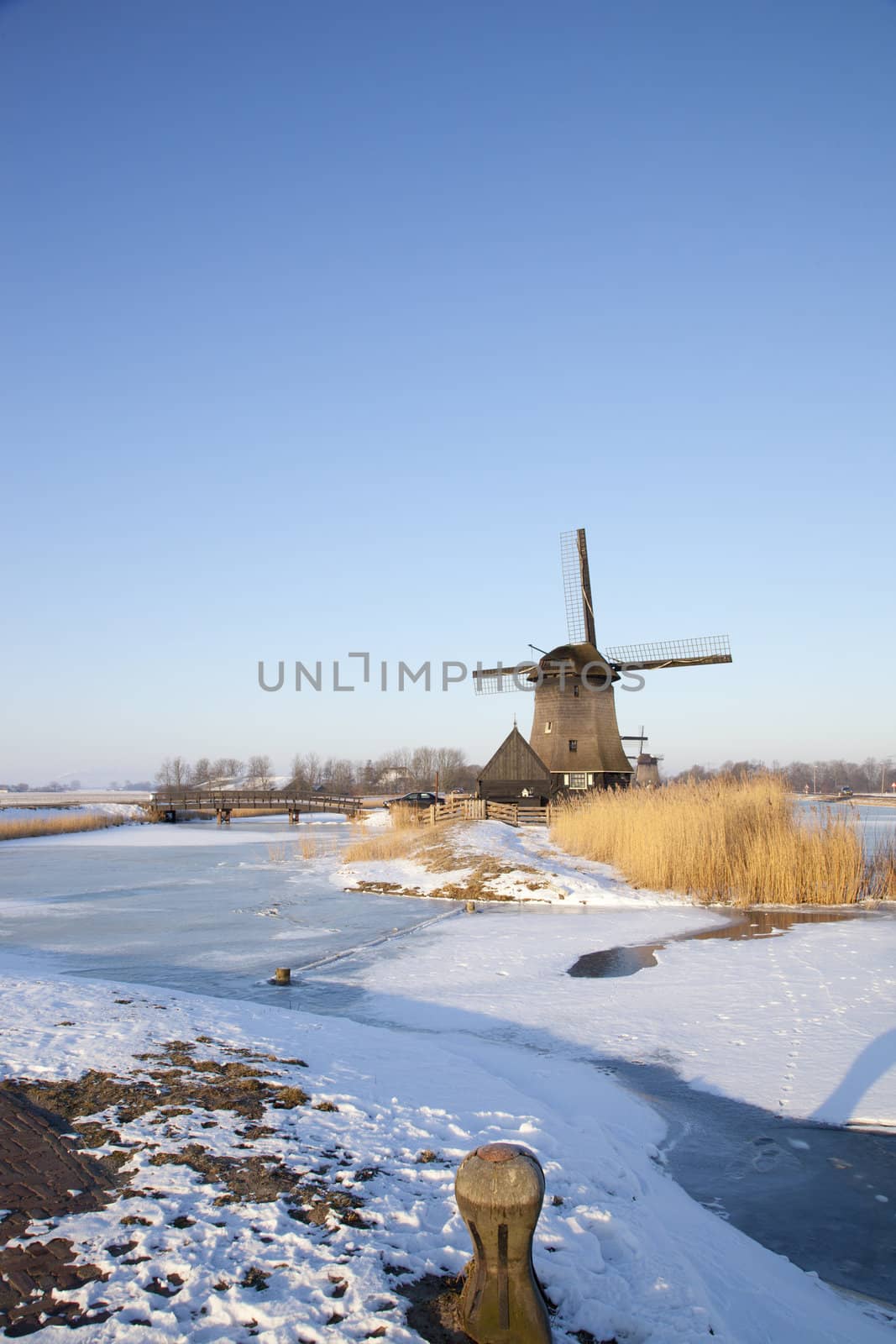 Windmill in winter time with snow and blue sky