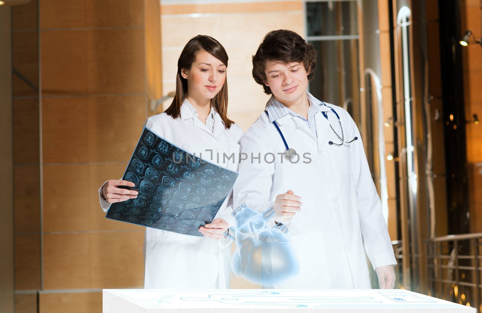 two doctors stand near glowing table discussing. projected objects on a desk