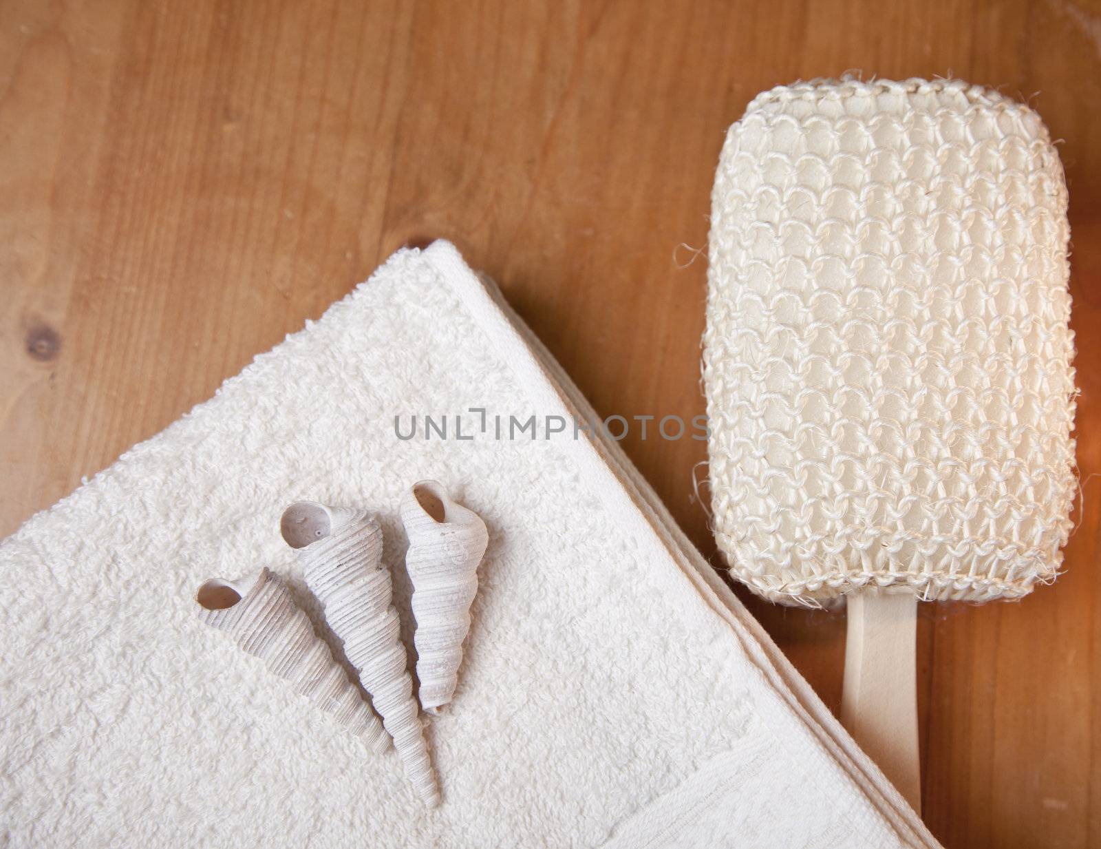 Luxury bath or shower set with towel, brush and shells on wooden background