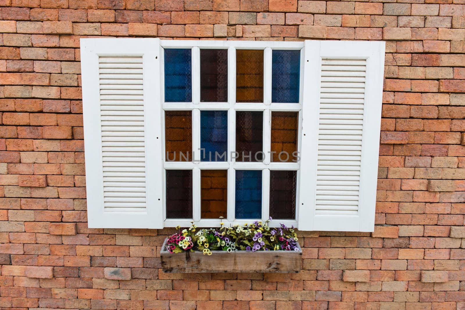 White window frame on a red brick wall with flowers, taken on a sunny day