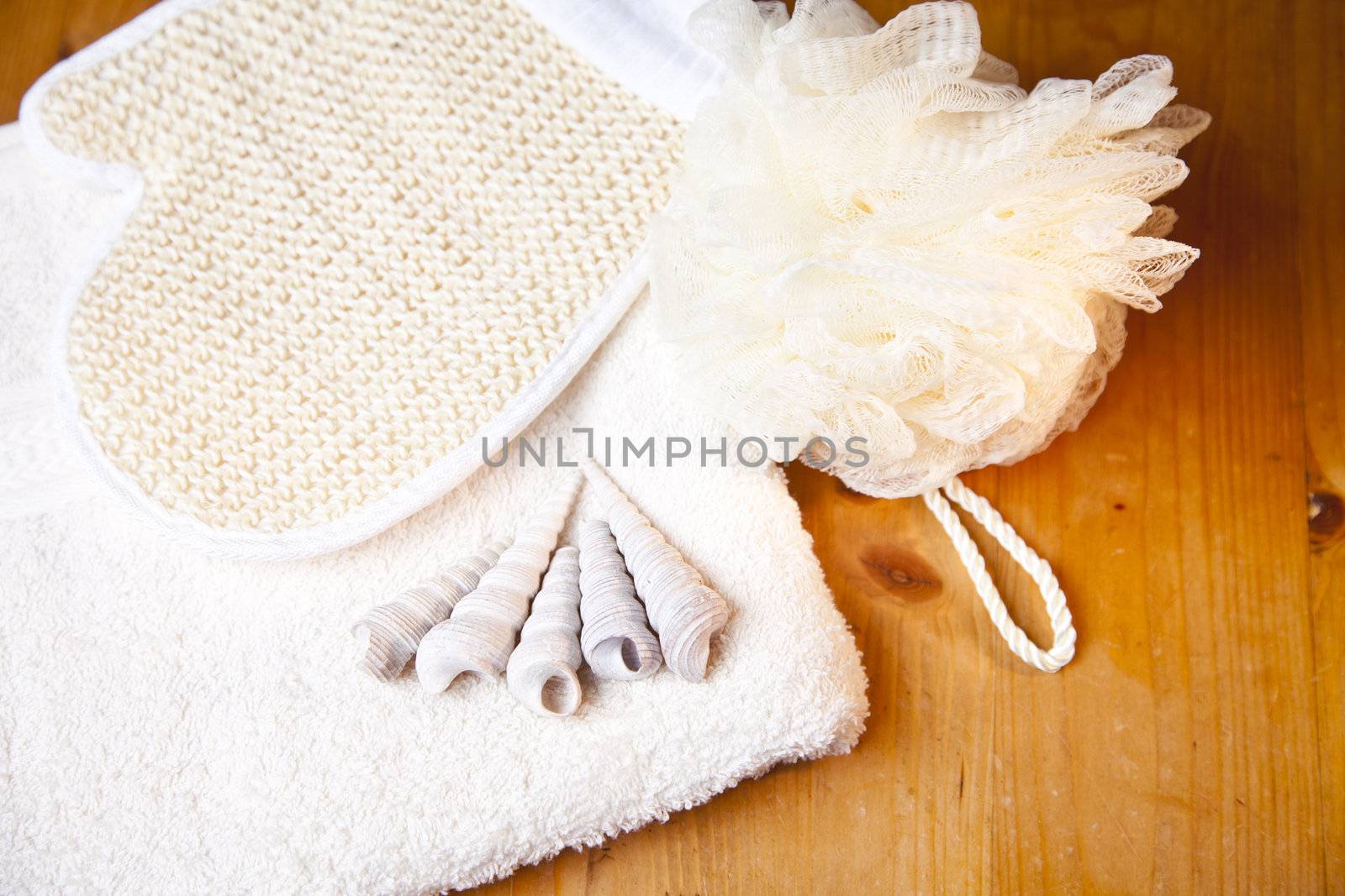 Luxury bath or shower set with towel, glove, sponge and shells on wooden background