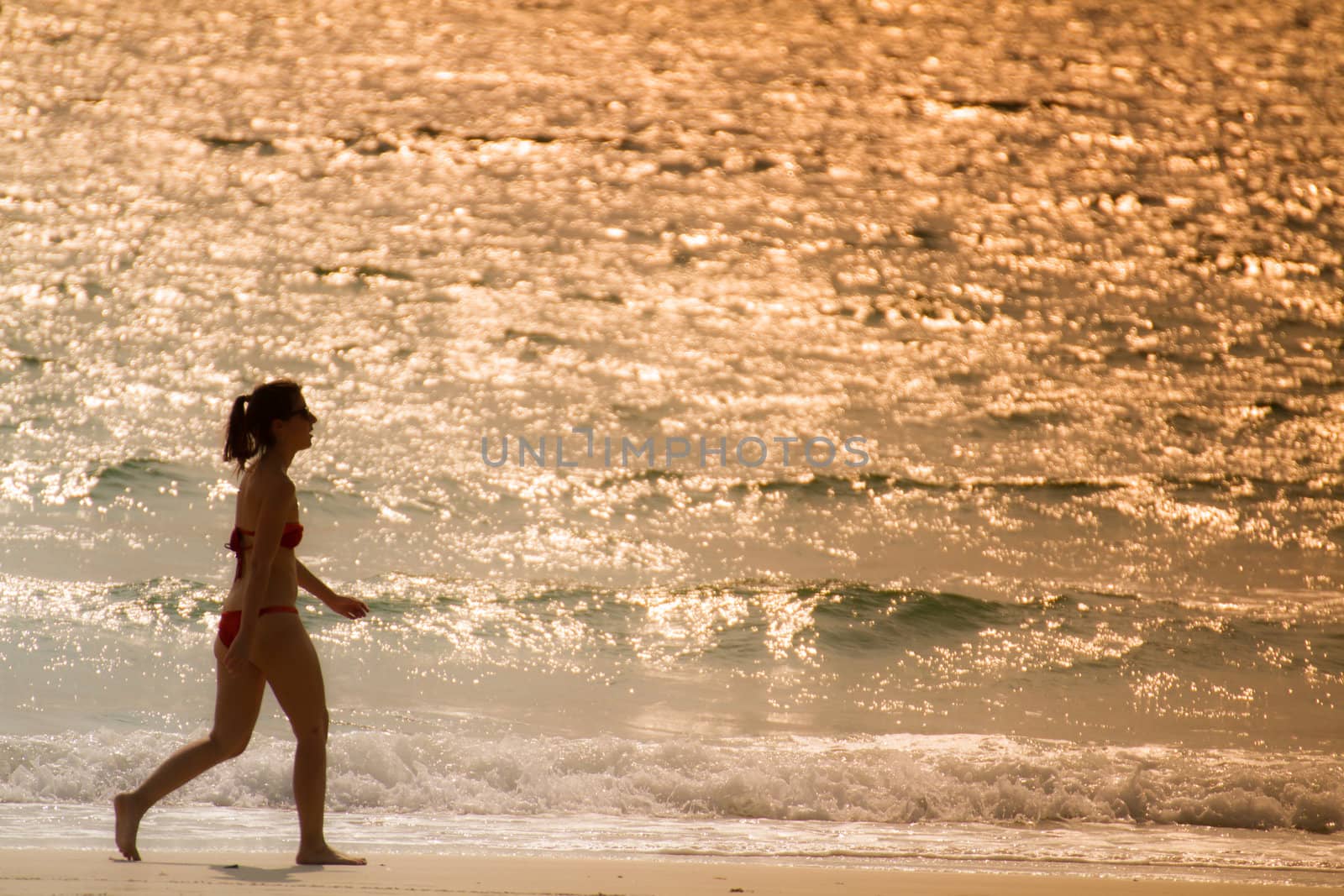 girl in red bigini walking on the beach