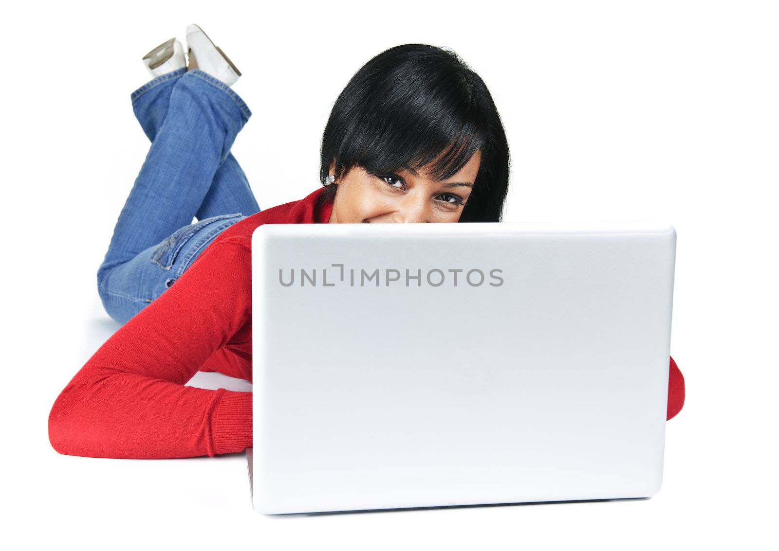 Smiling black woman peeking from behind computer laying on floor