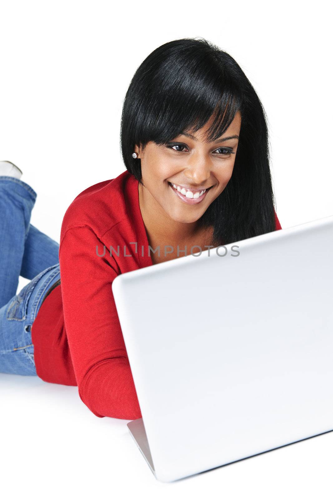 Smiling black woman typing on computer laying on floor