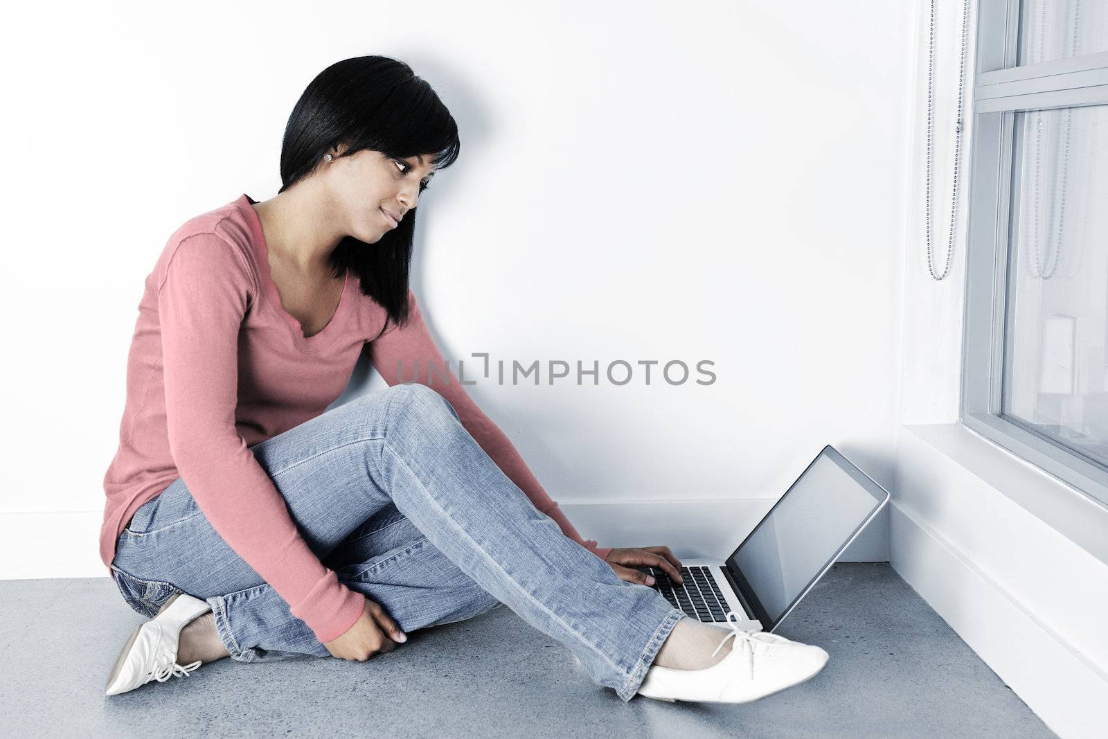 Young woman using laptop computer on floor by elenathewise