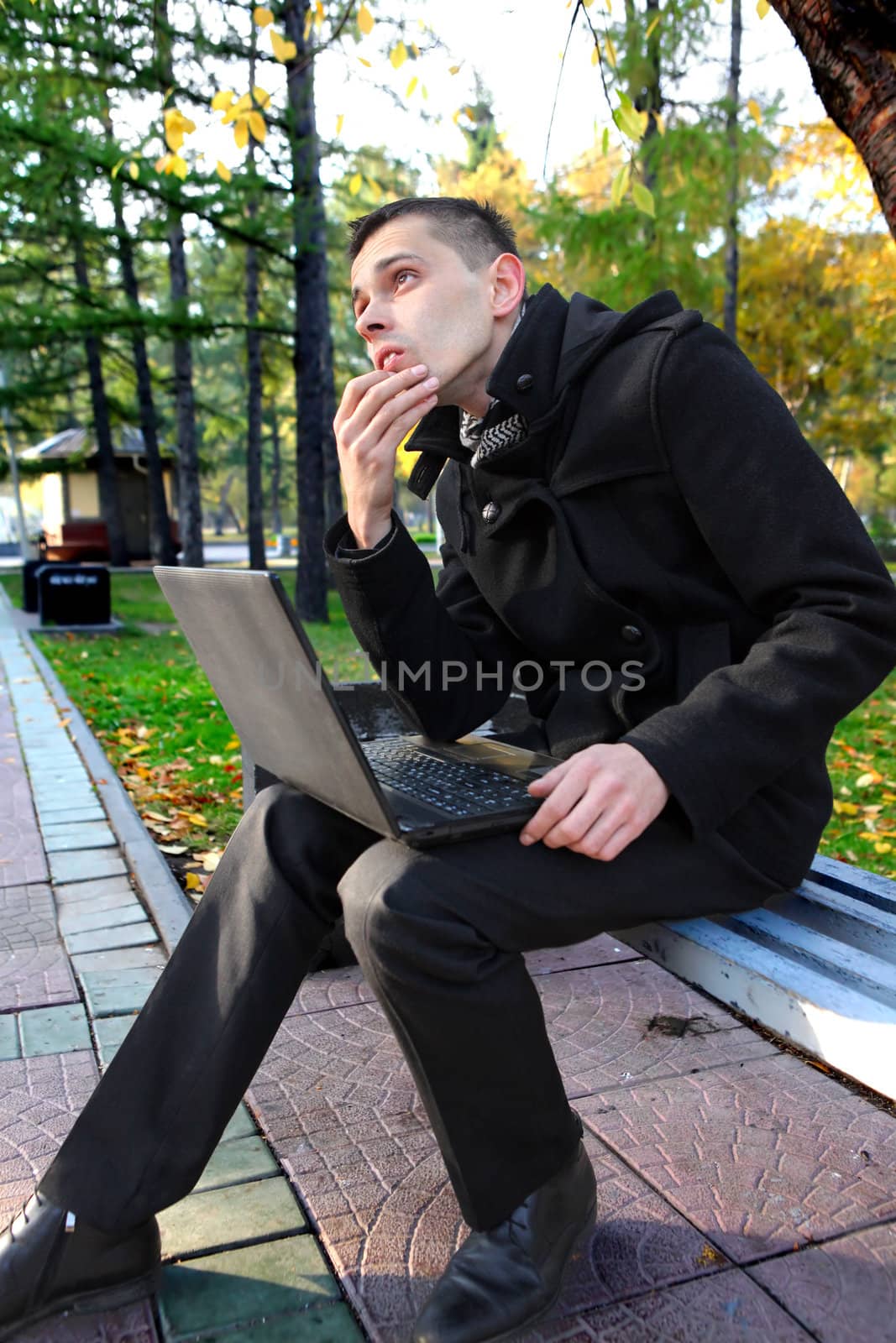 Pensive Young Man with Laptop Thinking at the Autumn Park