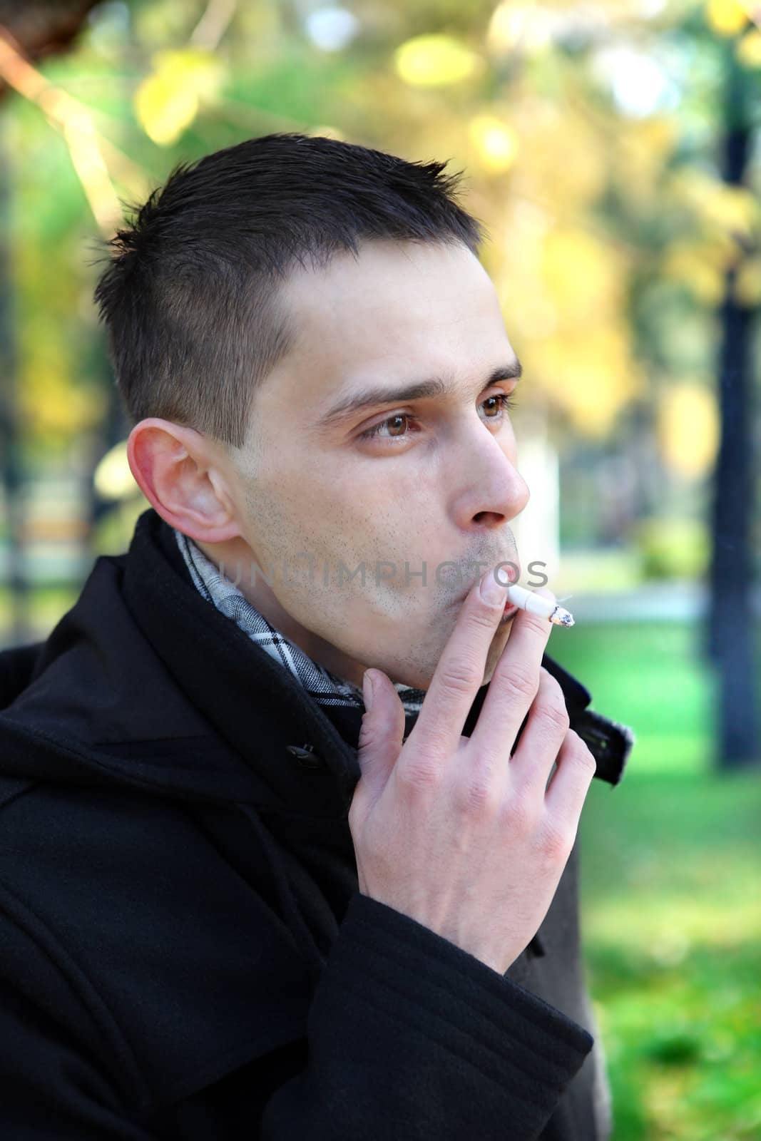 Man smoking cigarette in the autumn park