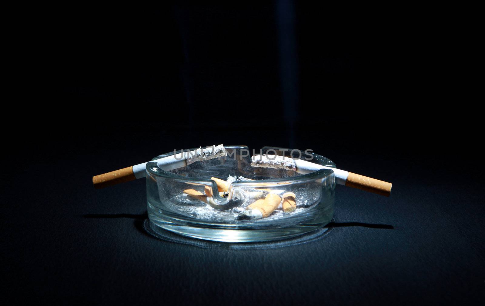 Dirty Ashtray And Two Cigarette On the Dark Background