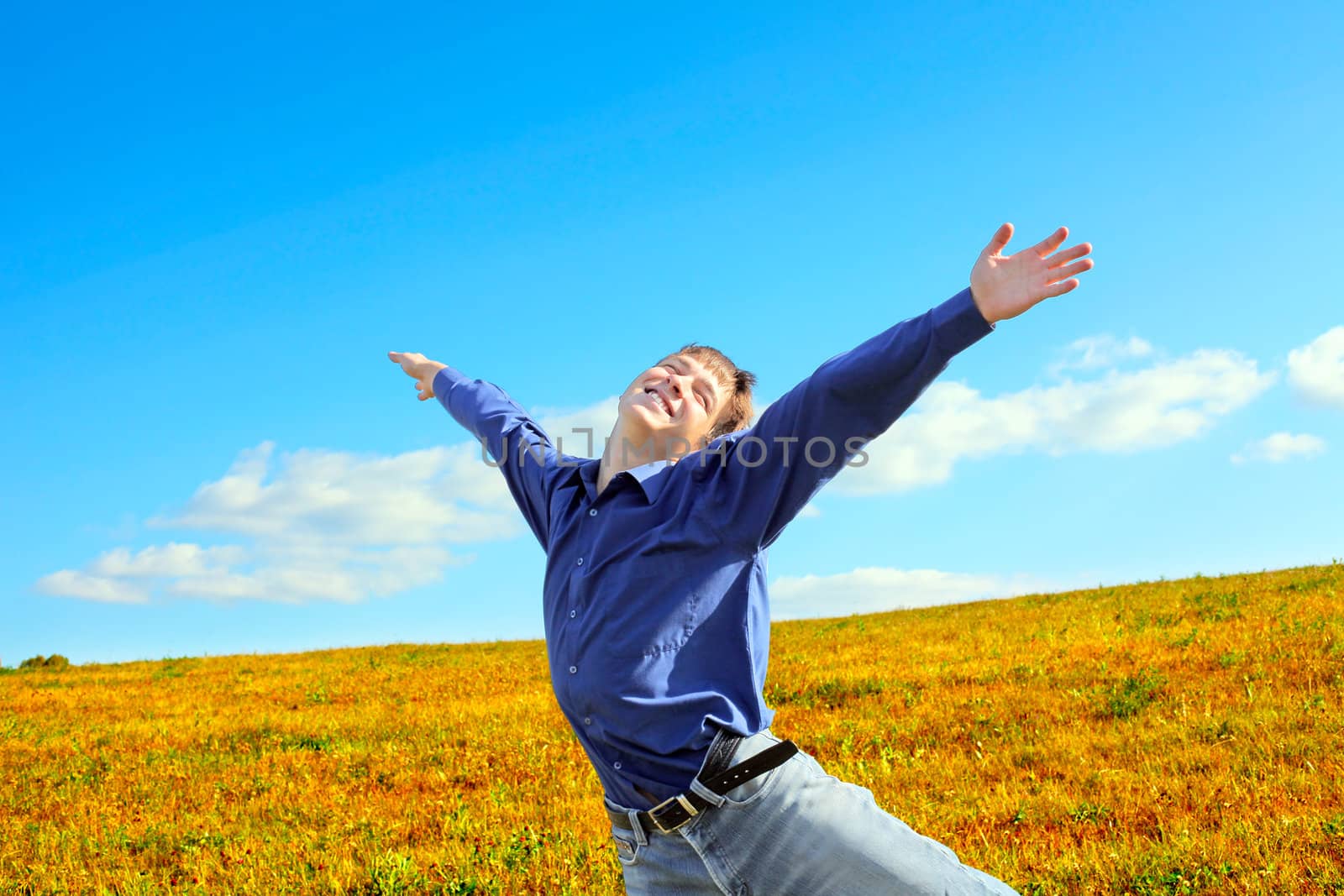 Happy Young Man raising his Hands in the Summer Field