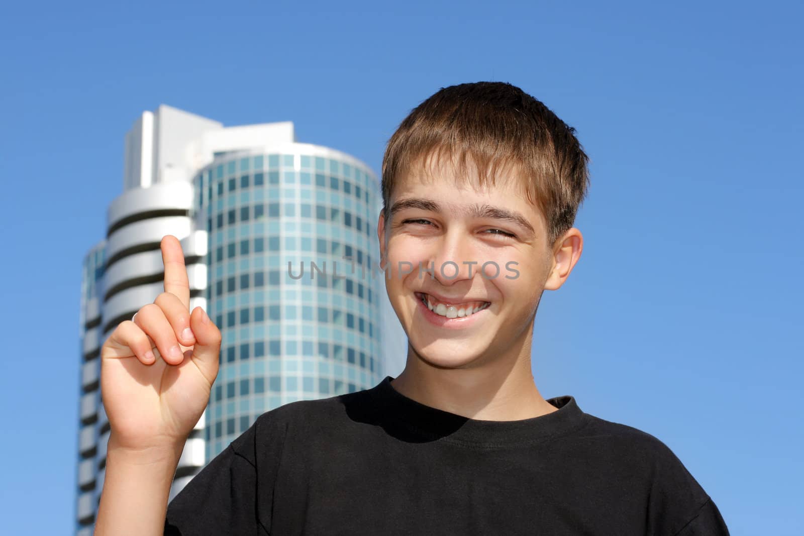 Happy Teenager with finger up on the glass building background