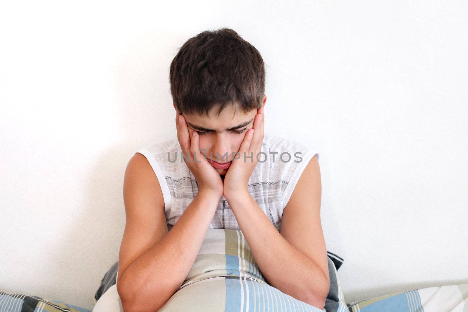 Sad Teenager feels toothache and sitting with pillow on the Bed in Home interior