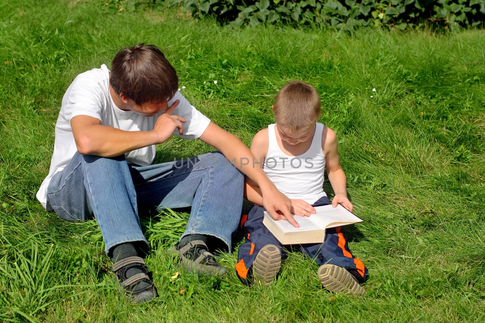 Little and Older Brothers reads a book in the Summer Park