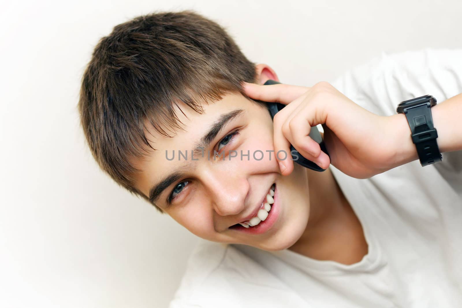 Happy Teenager speaking on the Phone. On the White Wall Background