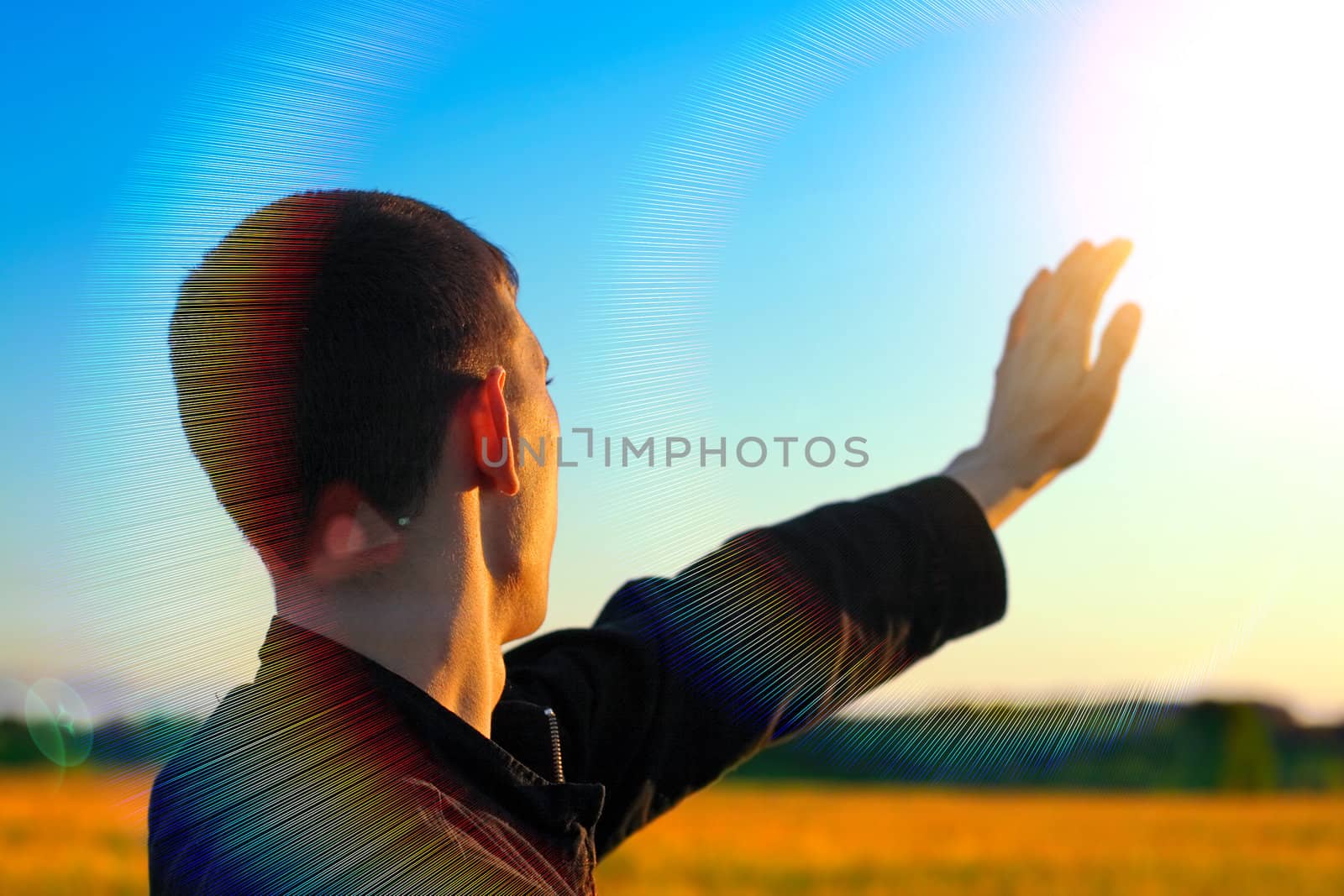 Young Man stretch his Hand to the Sunlight in the Evening Fields
