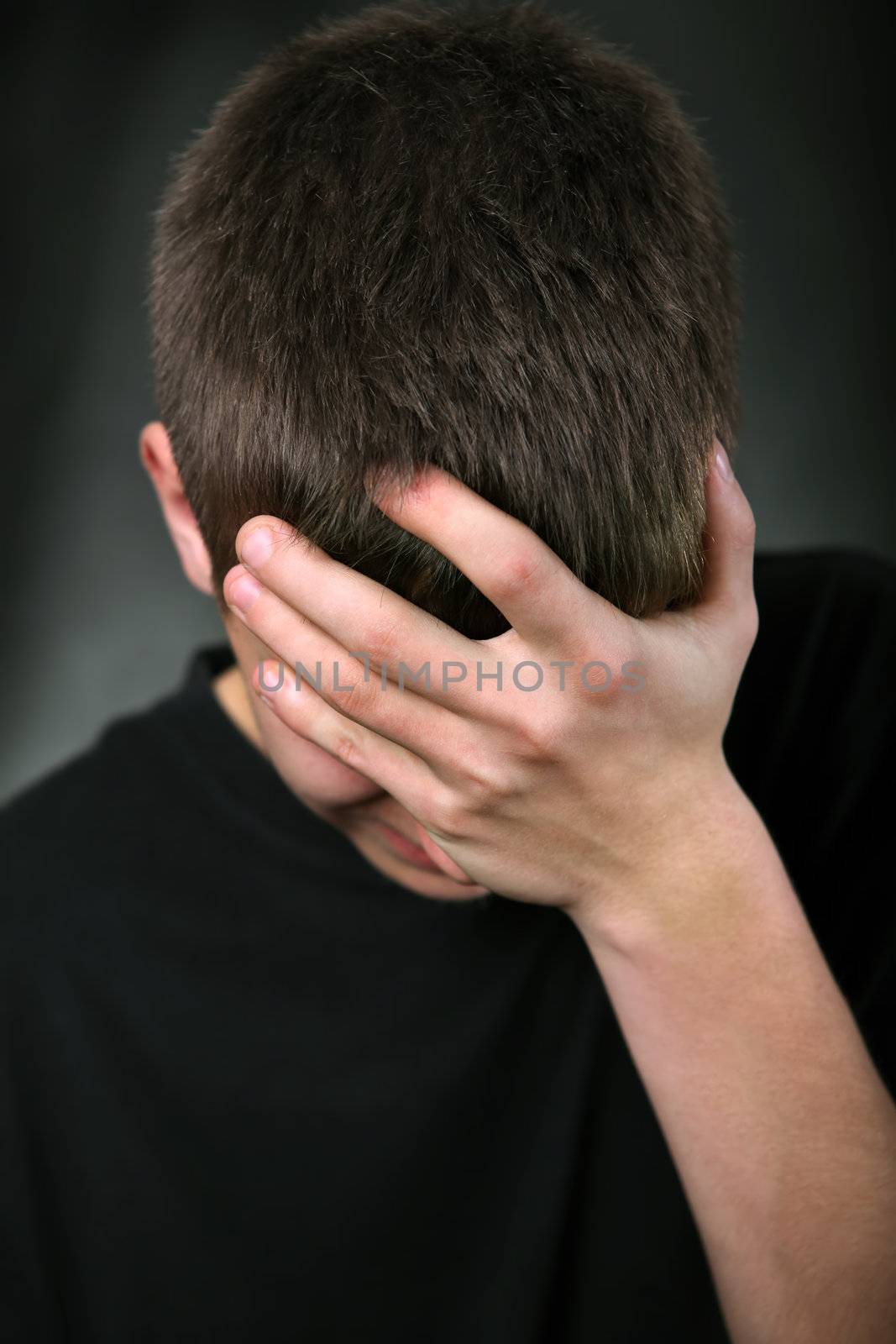 Sad Young Man On the Black Background hide his Face