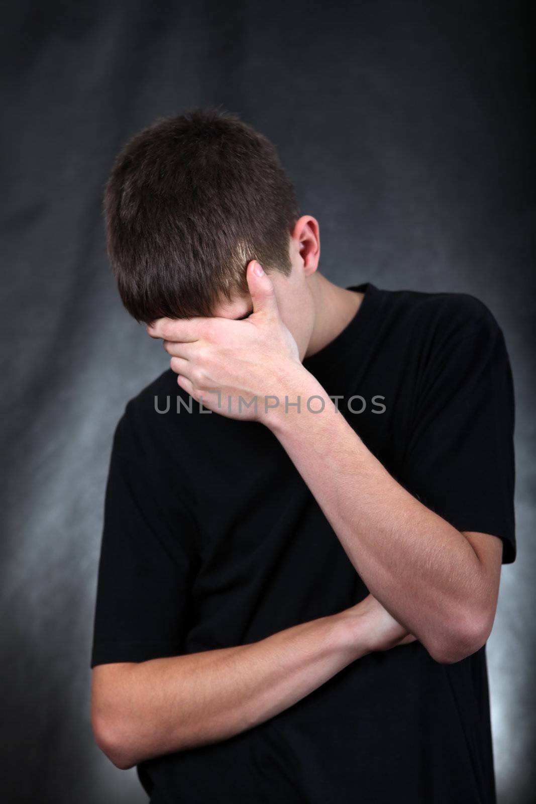 Sad Young Man On the Black Background hide his Face