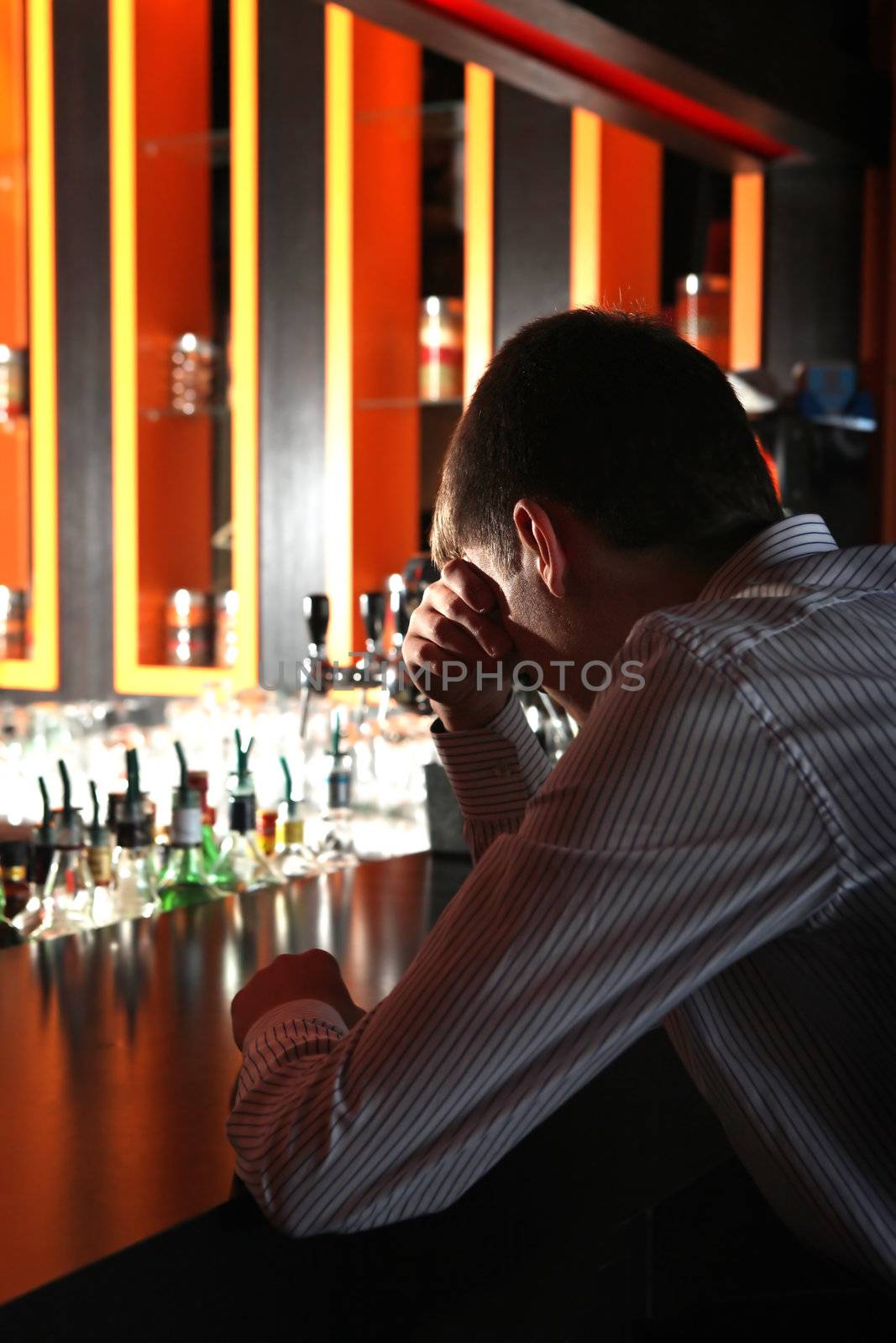 Sad and Lonely Young Man Sitting in the Darkness at the Bar counter