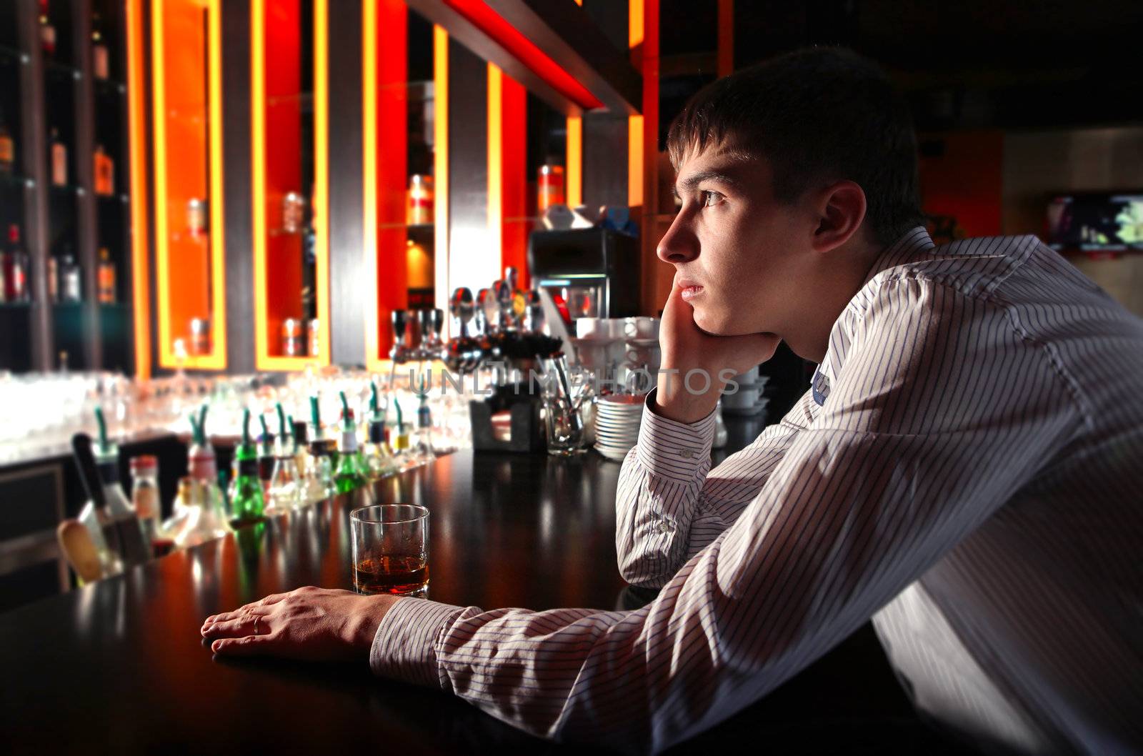 Sad and Lonely Young Man Sitting in the Darkness at the Bar counter