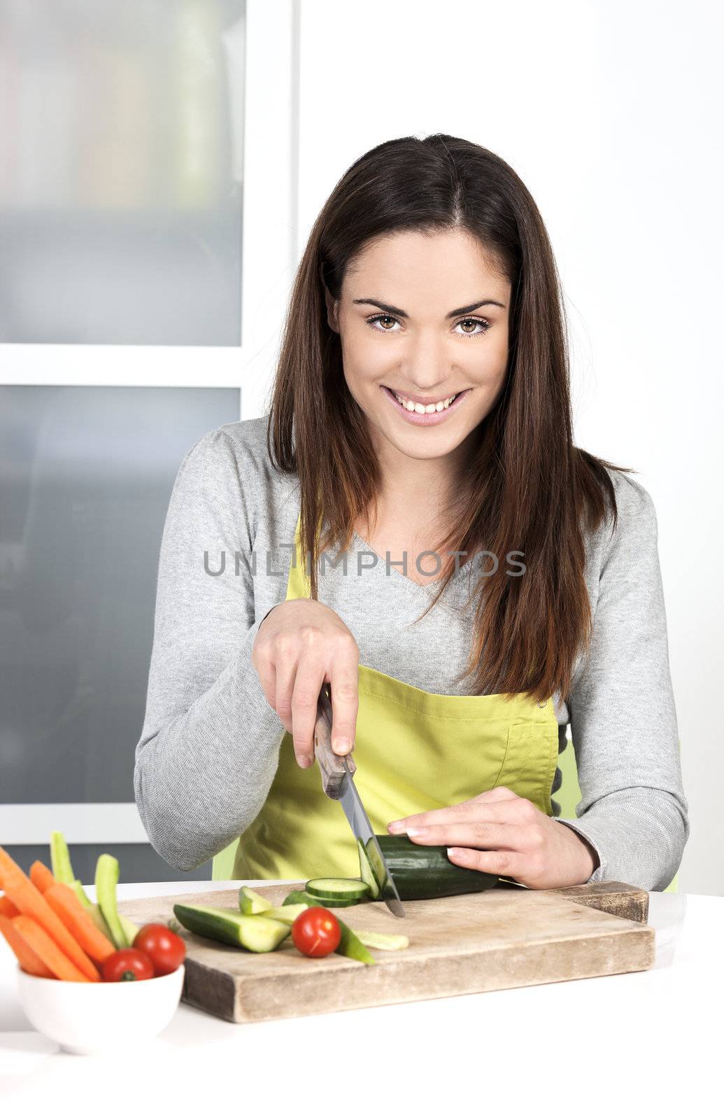 Woman cutting cucumber and in kitchen