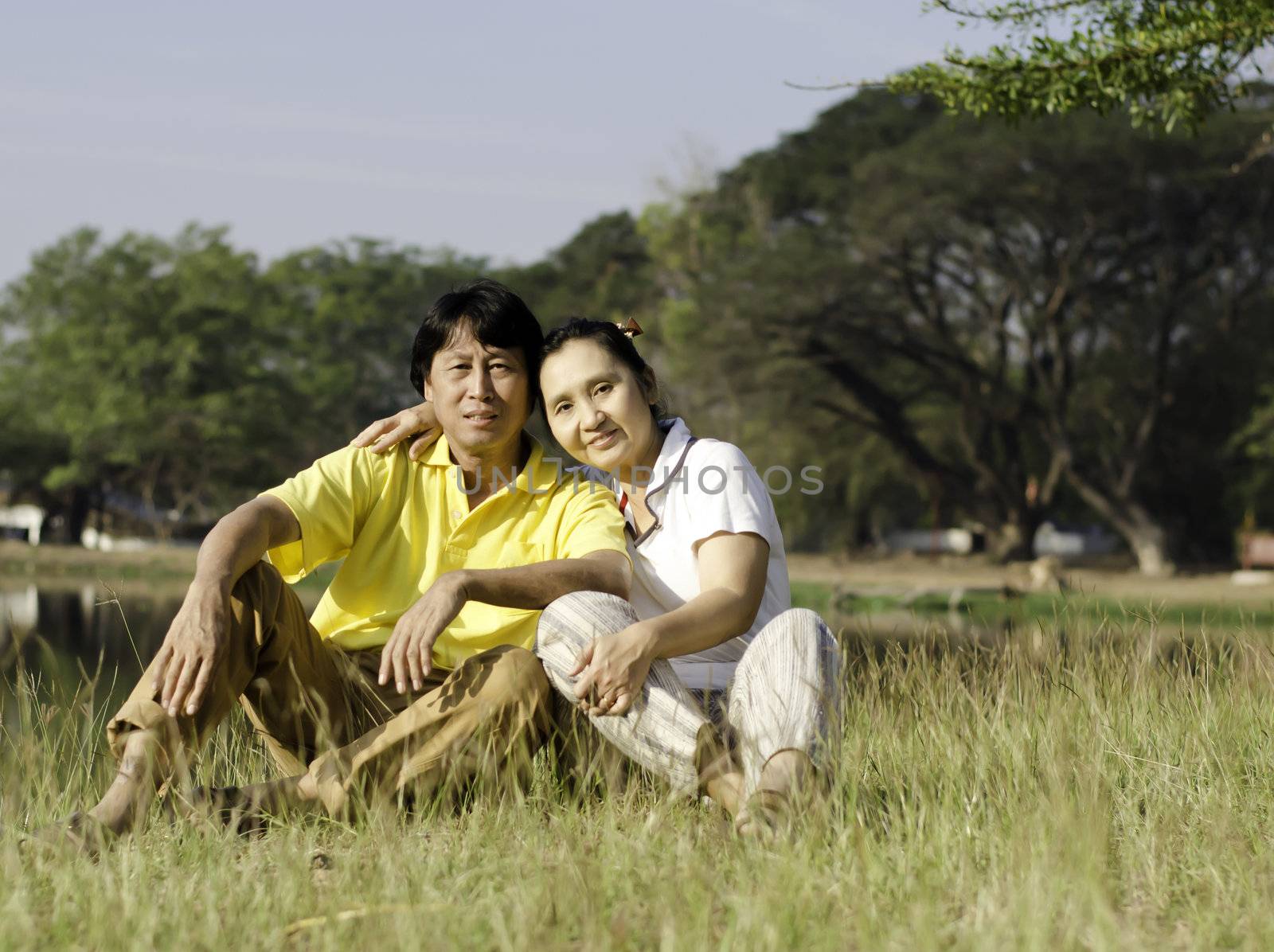 Portrait of beautiful couple sitting on ground in park relaxing 