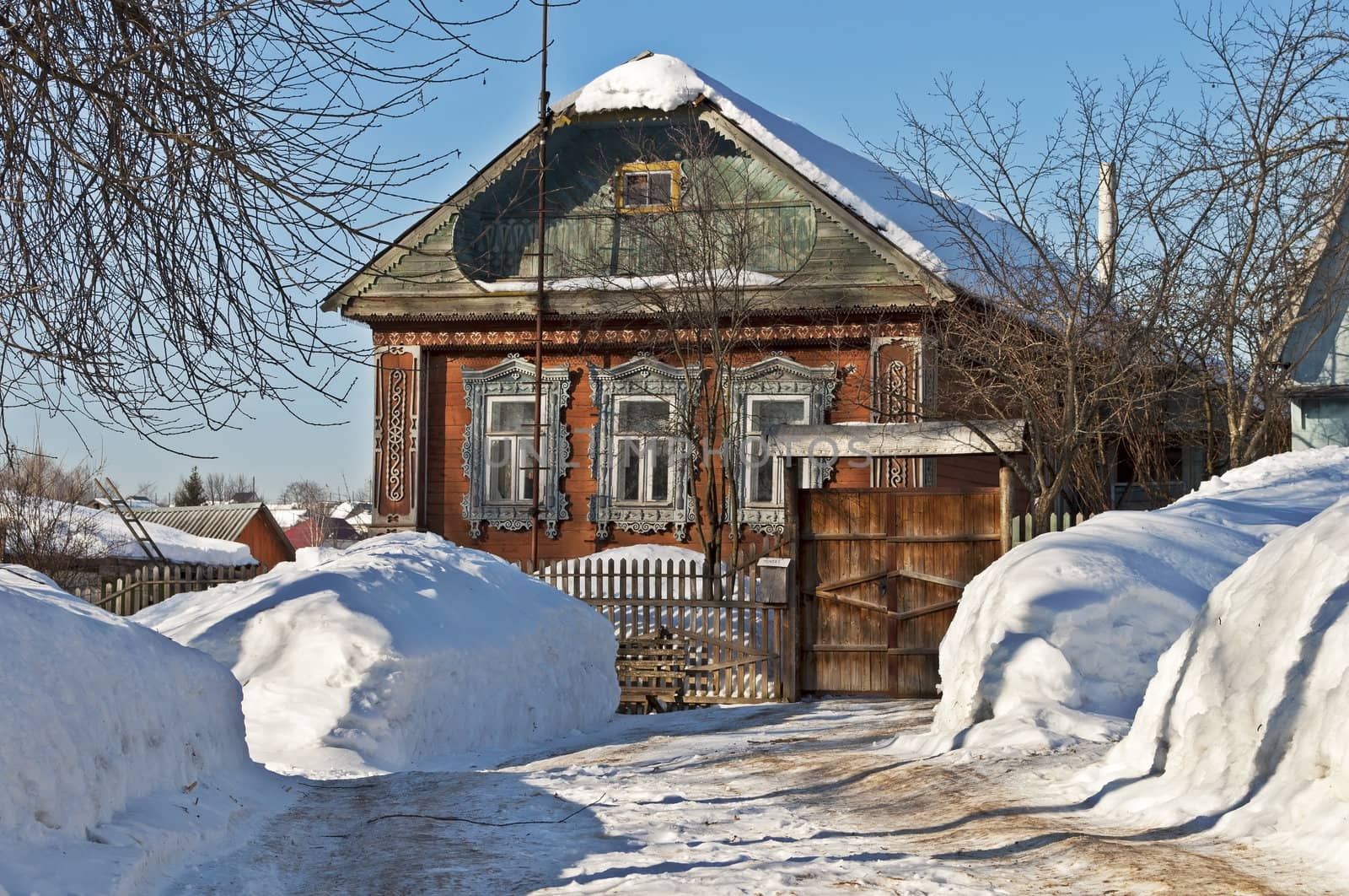 Old wooden house between snowdrifts, winter sunny day