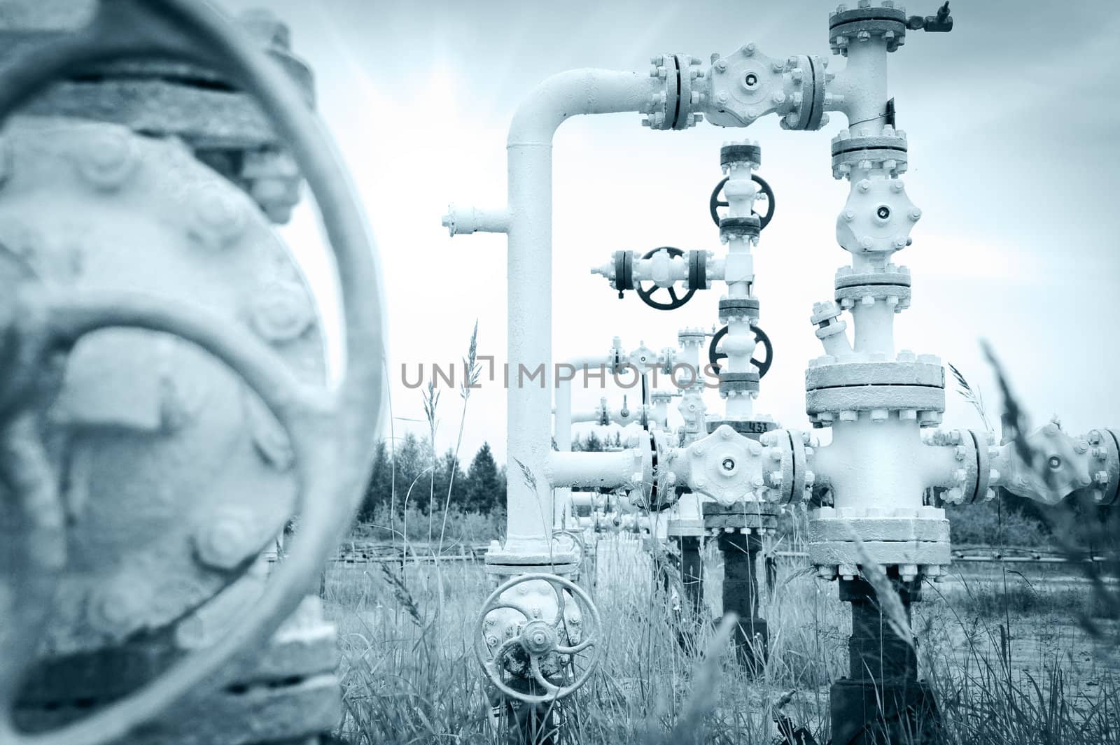 Oil, gas industry. Group wellheads and valve armature on a sky background. Toned.