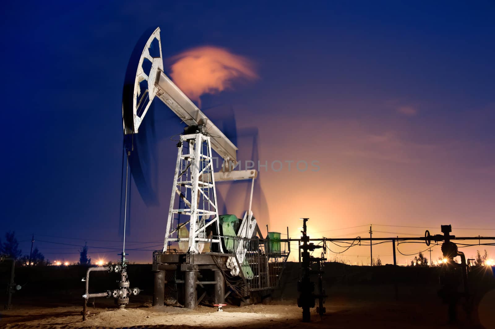 Oil pump-jack in action. Gas torches. Night view. Long exposure.