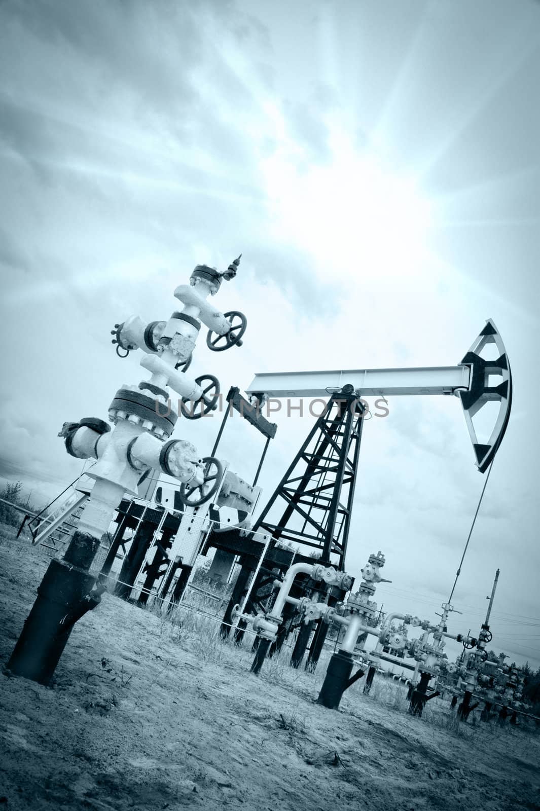 Extraction of oil. Pump jack and oil wellhead. Toned.
