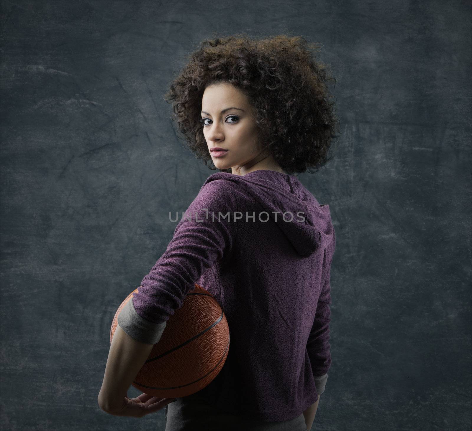 Portrait of young beautiful woman holding a basketball