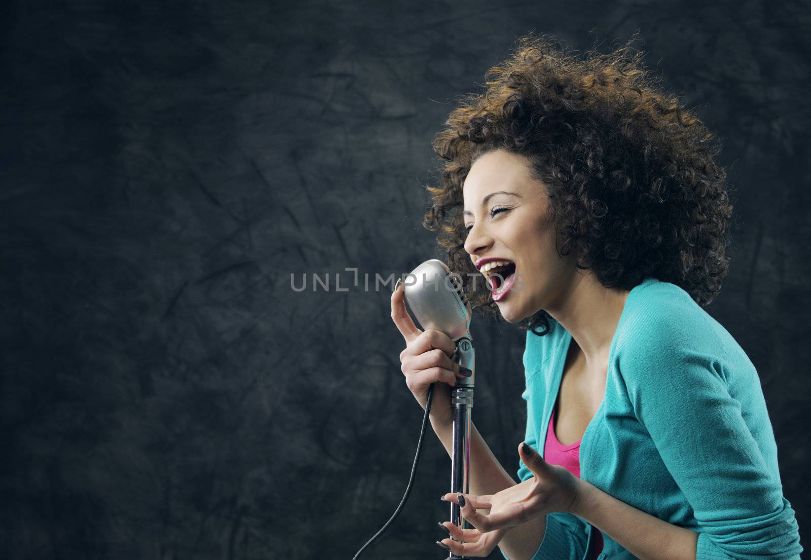 Young female singer with brown curly hair singing a song 
