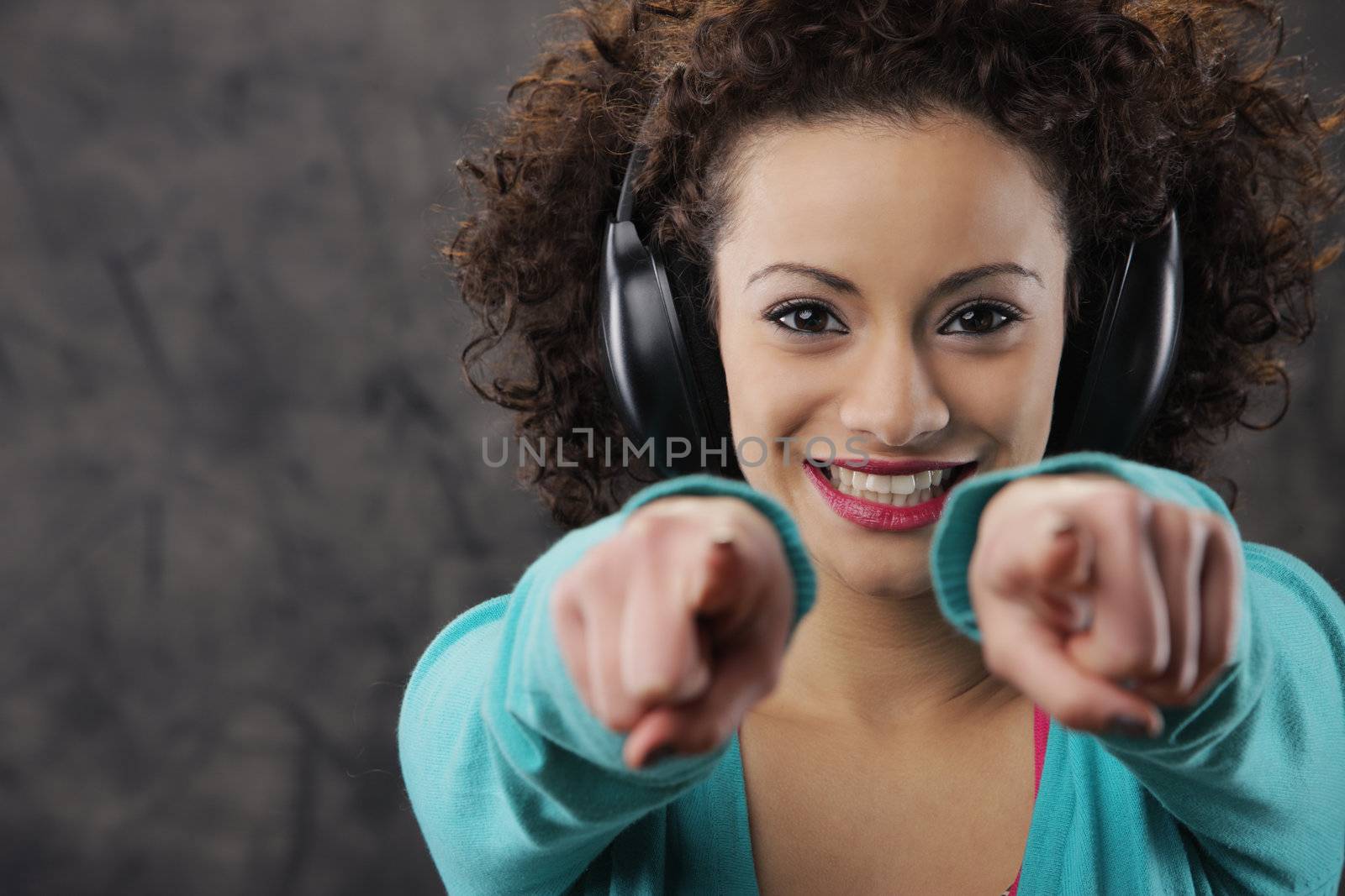 young woman enjoying music pointing at viewer