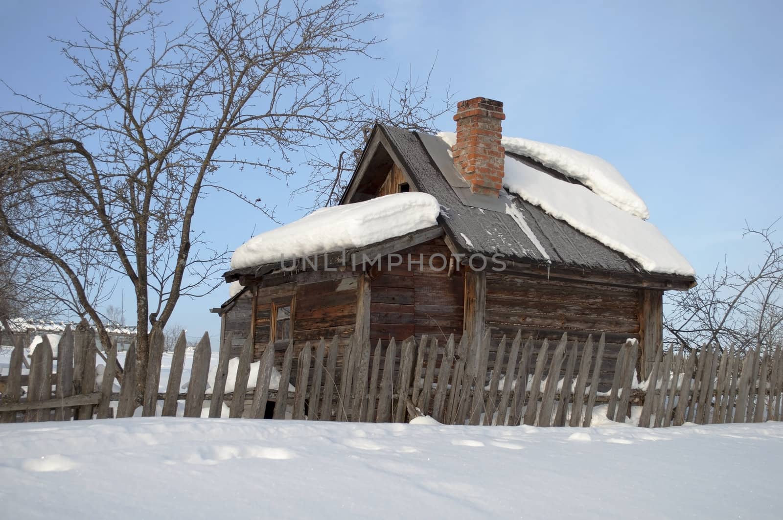 Old small wooden bathhouse among the snow drifts, winter sunny day