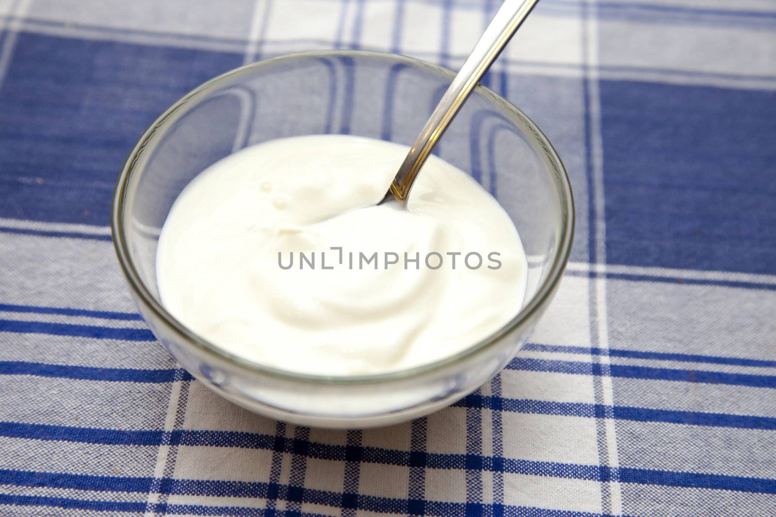 Yoghurt in a bowl with spoon on table
