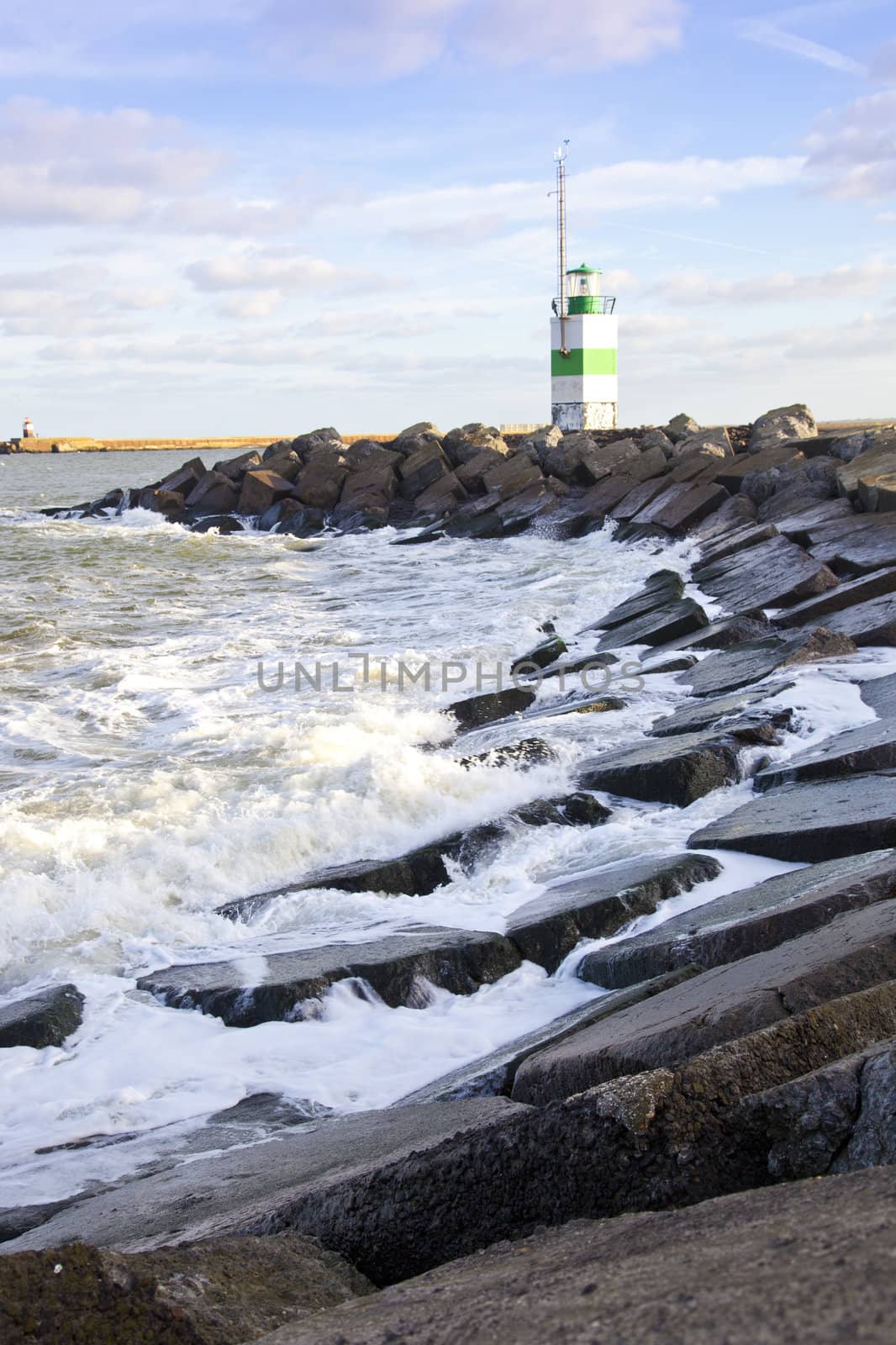 Little lighthouse with rocks and blue sky