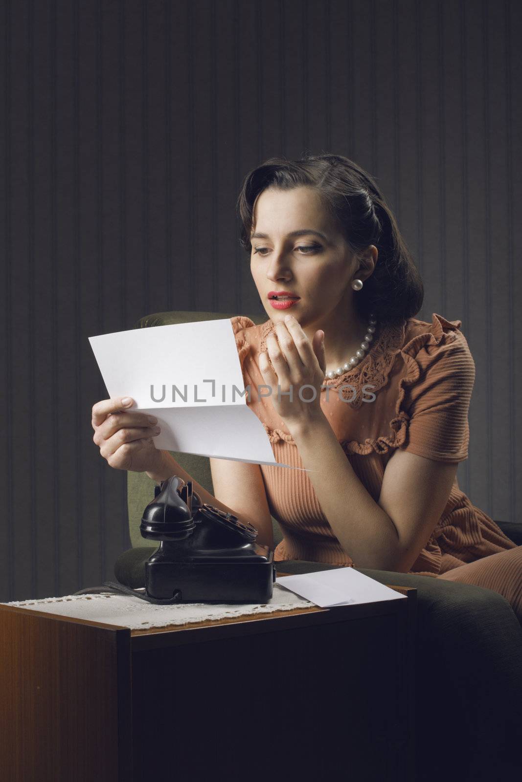Young woman reading a letter sitting on armchair