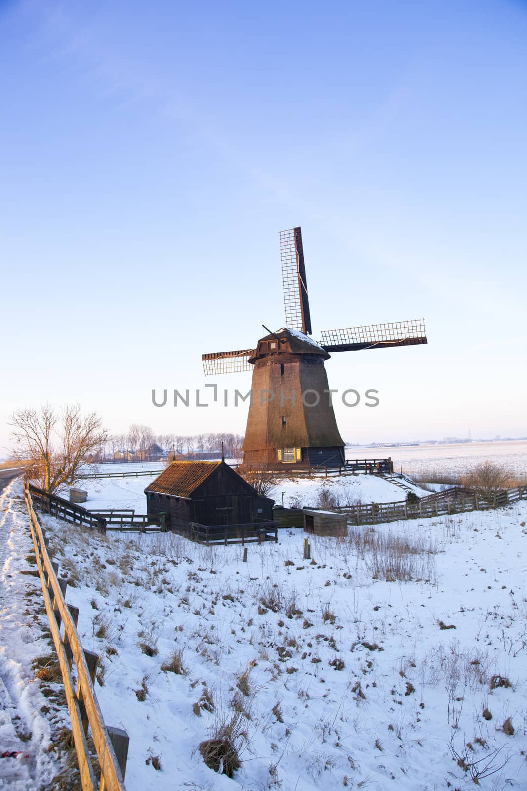 Windmill in winter time with snow and blue sky