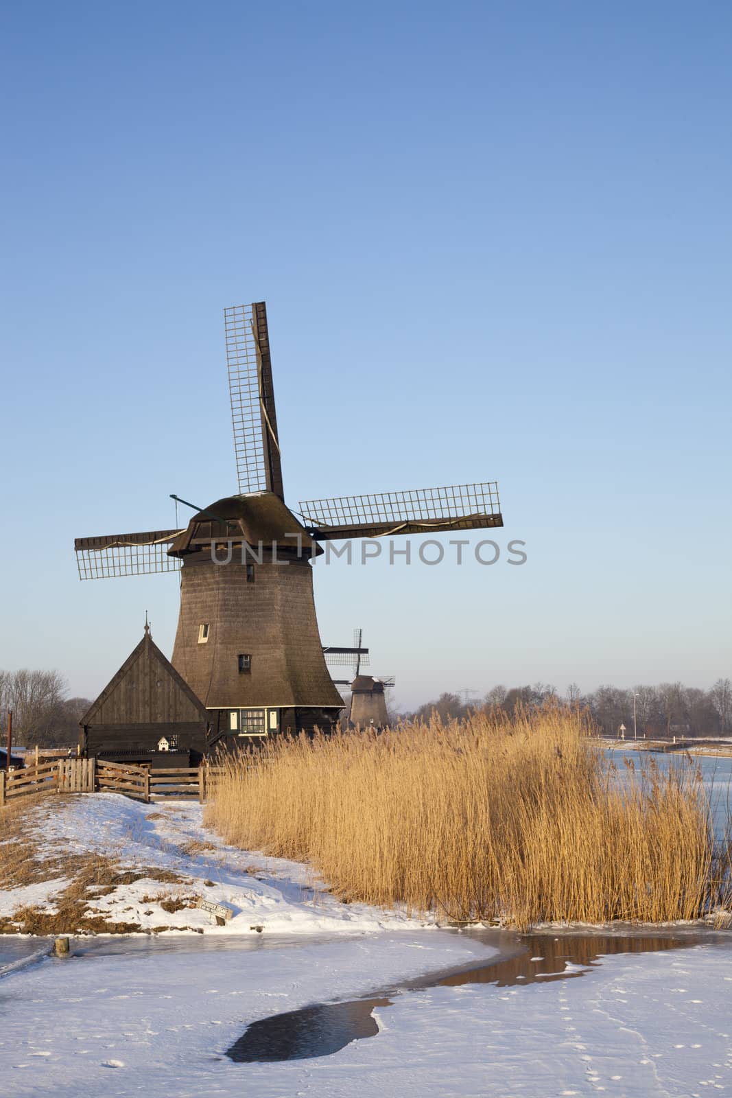 Windmill in winter time with snow, ice and blue sky