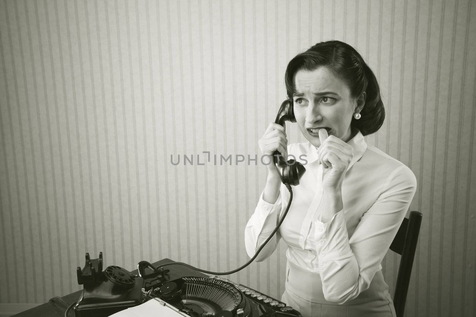 Woman embarrassed talking on phone at her desk