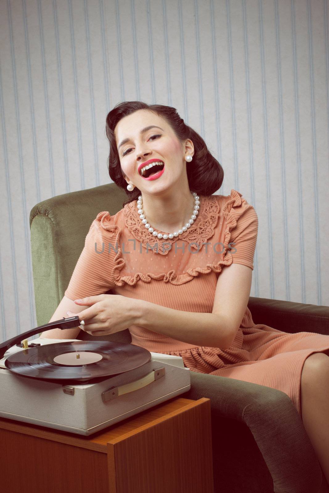 Smiling woman listening to music from a turntable