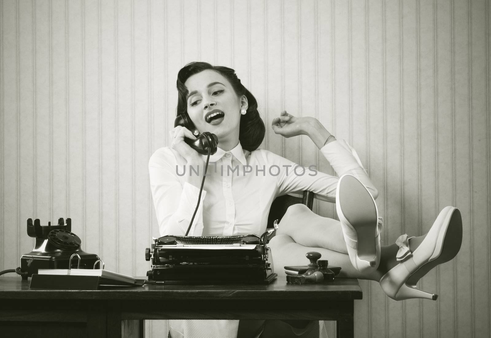 Business woman puts her feet up on her desk on the phone 