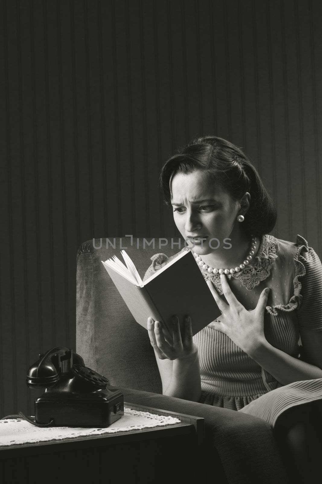 Woman sitting on armchair, reading a horror novel