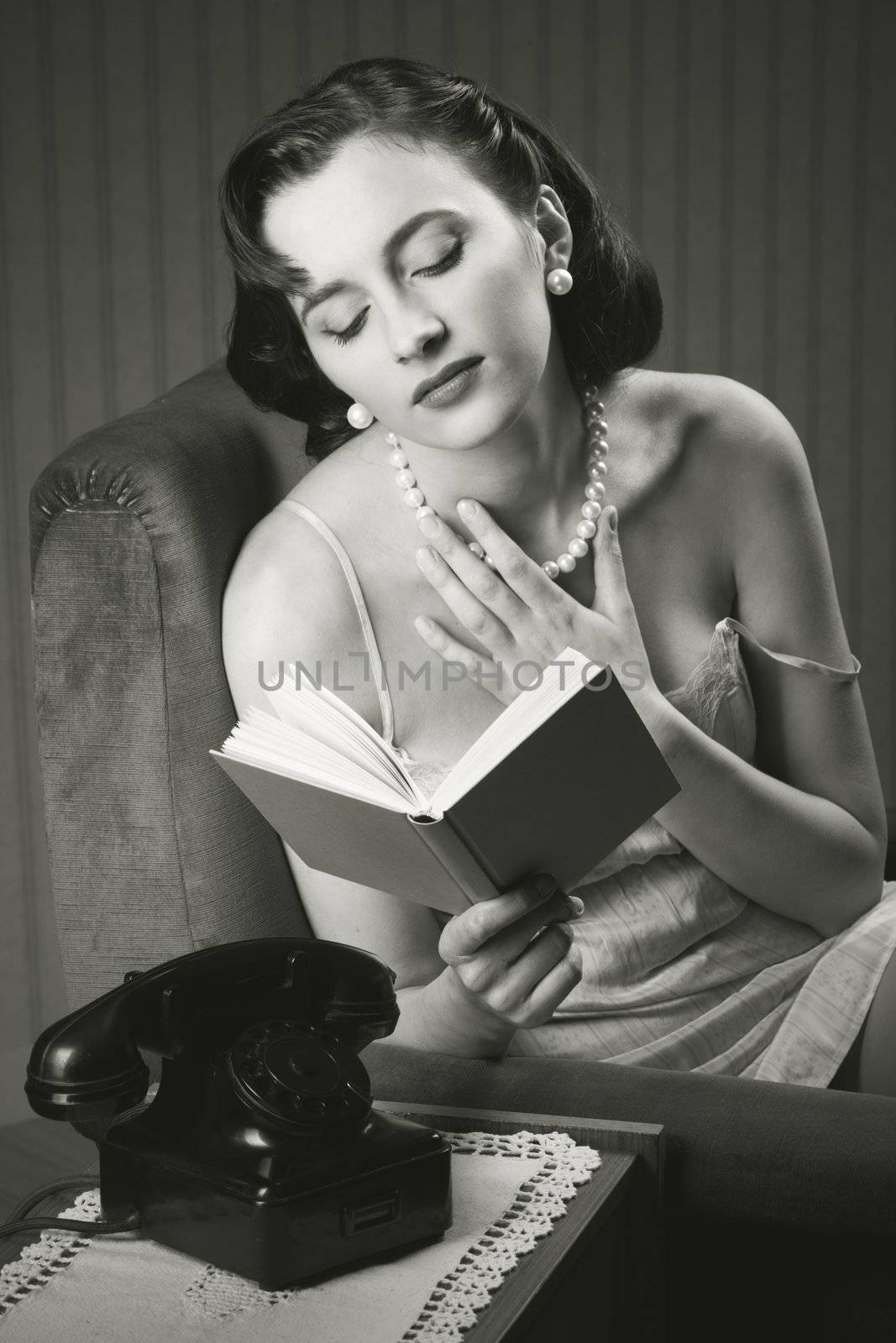 Sensual woman wearing lingerie reading a book on armchair