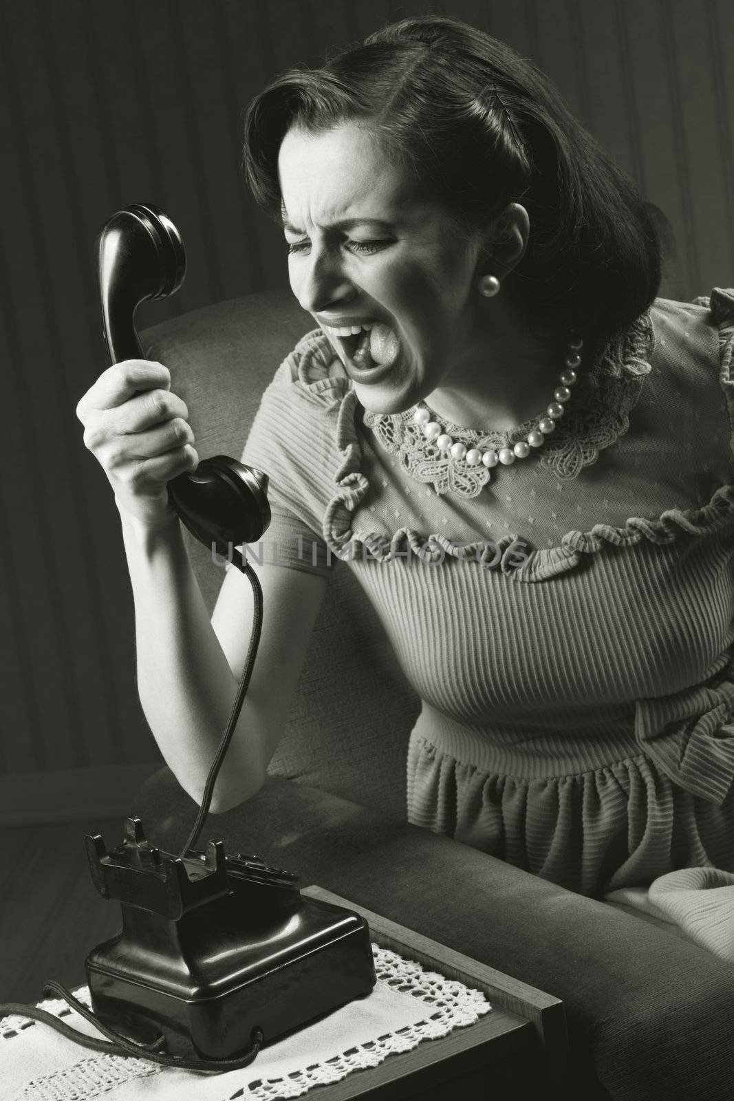 Angry woman screaming at retro phone, 1950 style 