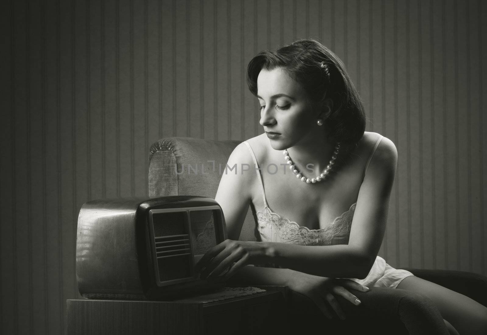 Sensual woman wearing lingerie listening music on old radio